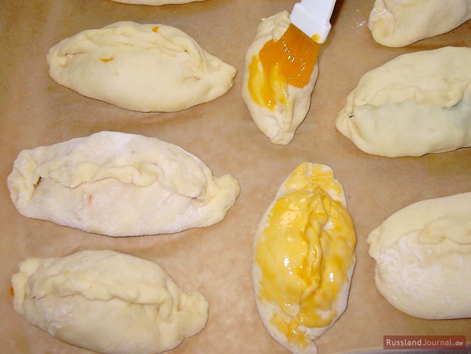 Arrange pierogi on a greased backing sheet leaving enough space between the pierogi so they can rise. Cover with a dishtowel and let pierogi rest for about 20 minutes. Mix an egg yolk with butter and brush pierogi with this mixture.