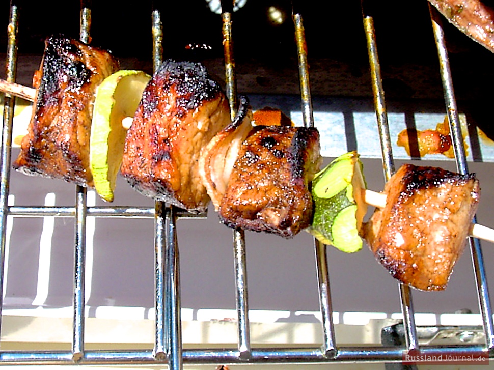 Grilling marinated shashlik preparing on a barbecue grill over charcoal.  Shashlik is a form of Shish kebab popular in Eastern Europe. Shashlyk (meaning  skewered meat) was originally made of lamb. Stock Photo