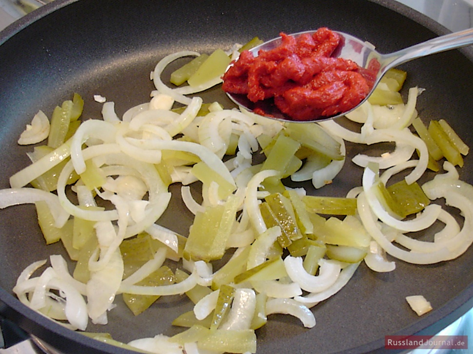 Cut pickled cucumbers in stripes. Put the cucumbers and the tomato paste into the pan and stir for a couple of minutes.