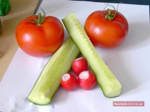 Zwei Tomaten, aufgeschnittene Gurke und drei Radischen
