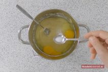 Gelber Teig und zwei Eier im Topf, Backpulver vom Teelöffel streuen