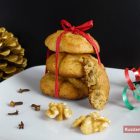 Drei Lebkuchen aufeinander gebunden mit roter Schleife auf weißem Teller mit Walnüssen und Nelken