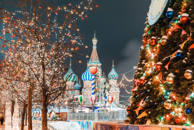 Roter Platz in Moskau mit Silvester und Weihnachtsdekoration. Blick auf die Basilius-Kathedrale, geschmückter Tannenbaum, Bäume mit roten und goldenen Kugeln.