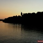 Dunkler Wald mit Lenin-Denkmal am Fluss in Russland