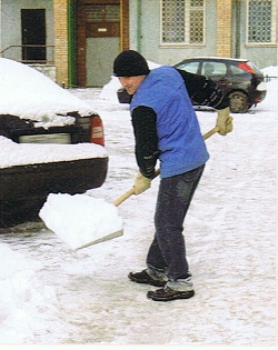 Mann in blauer Weste schaufelt Schnee im Hof, ein Foto aus dem MOCT 1 Russisch Lehrbuch für Anfänger