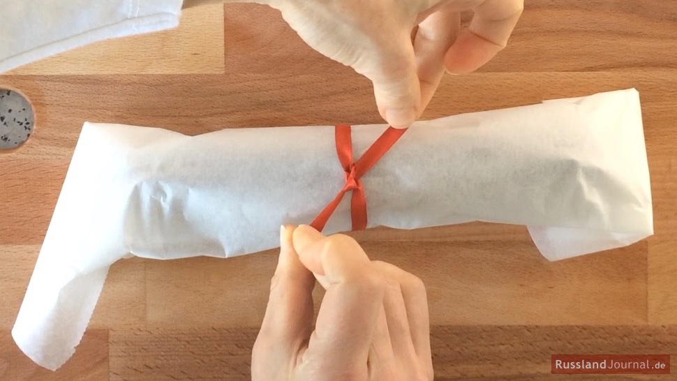 Süße Wurst in Butterbrotpapier mit rotem Schleifchen