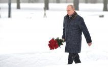 Putin mit einem Rosenstrauß im Winter am Piskarjowskoje-Gedenkfriedhof anlässlich des 75. Jahrestages des Durchbruchs der Leningrader Blockade