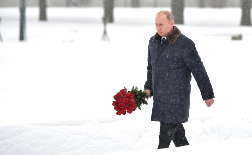 Putin mit einem Rosenstrauß im Winter am Piskarjowskoje-Gedenkfriedhof anlässlich des 75. Jahrestages des Durchbruchs der Leningrader Blockade