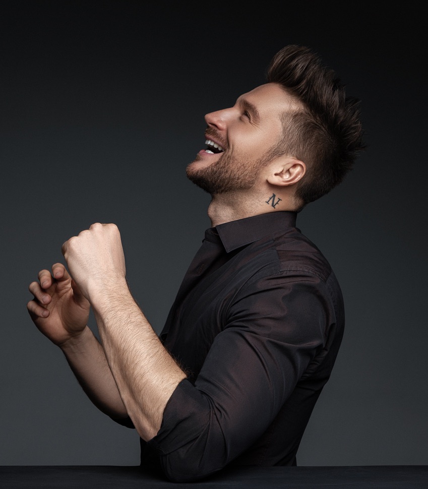 Sergey Lazarev seitlich im schwarzen Hemd mit N Tattoo