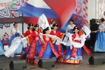 Frauen in weiß-blau-roten Kleidern tanzen ein Volkstanz beim "Samowarfest" auf WDNCh