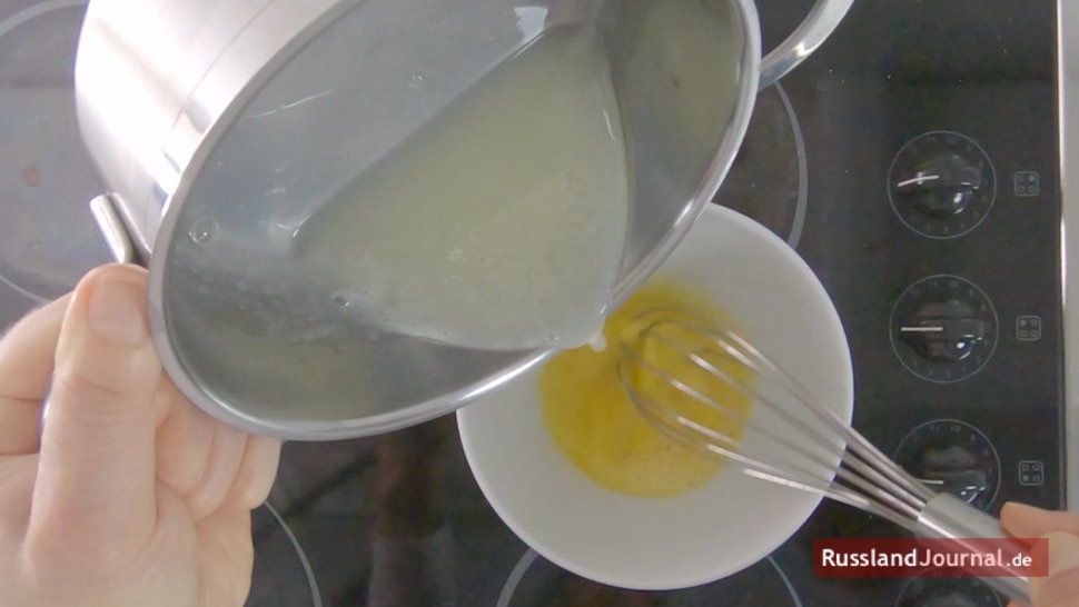 Milch-Zucker-Mischung rinnt in eine Schüssel mit geschlagenem Ei gießen