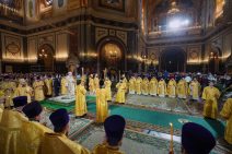 Patriarch auf dem Podest und die Geistlichen mit Kerzen